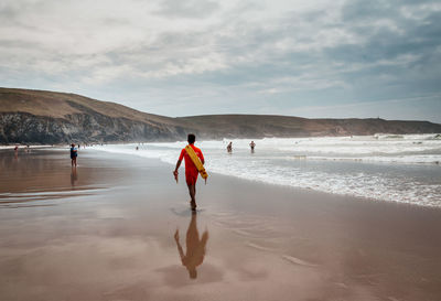 Rear view of men on beach against sky