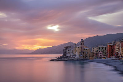 Scenic view of sea by buildings against sky during sunset