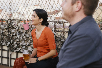 Young couple sitting by fence