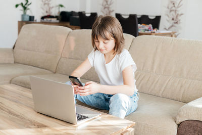 Distance learning. the girl sits at home on the couch and studies using a laptop or makes calls