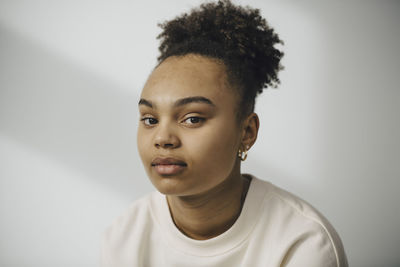 Portrait of young woman against white wall