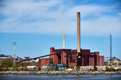 Factory by river against sky