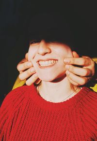 Close-up of smiling young woman against black background