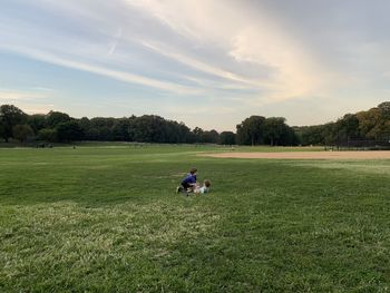 Two boys playing on a wide park lawn against summer sky
