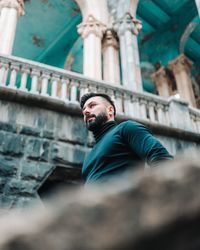 Low angle view of man sitting against building