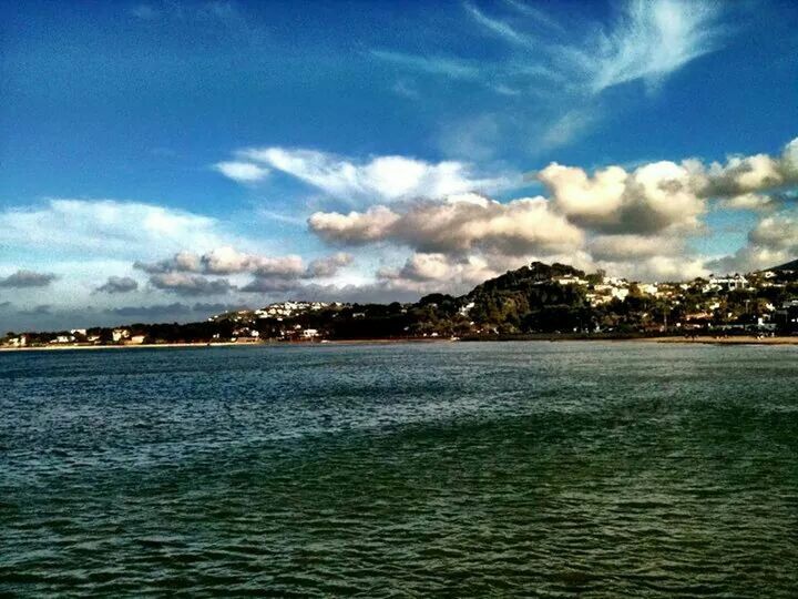 water, waterfront, sky, blue, city, building exterior, architecture, built structure, river, cloud - sky, scenics, sea, cityscape, rippled, tranquil scene, beauty in nature, nature, cloud, tranquility, outdoors