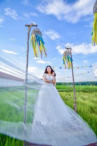 Young bride standing on field against sky