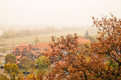 Trees and houses against sky during autumn