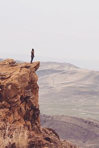 Woman standing on rock against clear sky