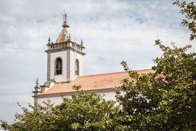 Low angle view of trees and building against sky