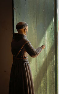 Woman wearing hat standing against wall