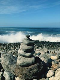 Stacked stones on shore at beach during sunny day