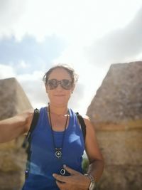 Portrait of woman in sunglasses standing against rocks