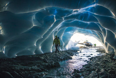 Ice climber enters ice cave to find a climbing route.