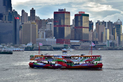 Nautical vessel on sea by buildings against sky in city