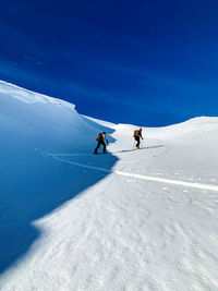 People skiing on snowcapped mountain against sky