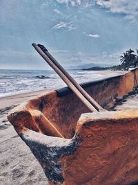 Driftwood on beach by sea against sky