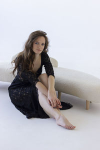 Young woman sitting on sofa against white background