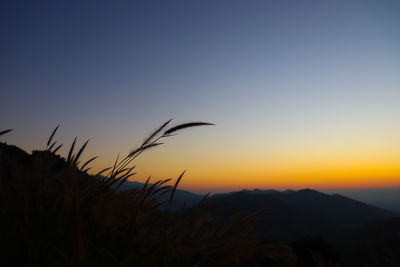 Silhouette landscape against orange sky