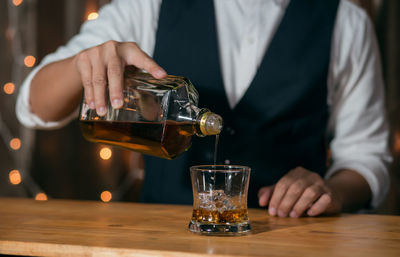 Midsection of man drinking glasses on table