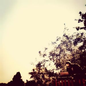 Side view of silhouette woman sitting against sky at sunset