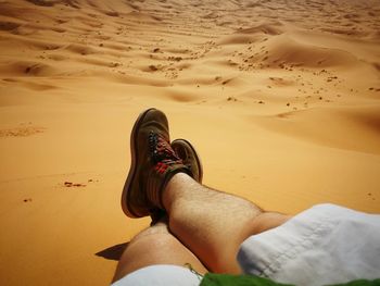 Low section of man relaxing at desert