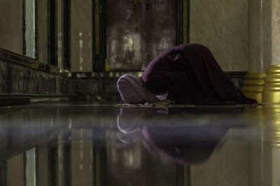 Midsection of woman sitting on floor in building