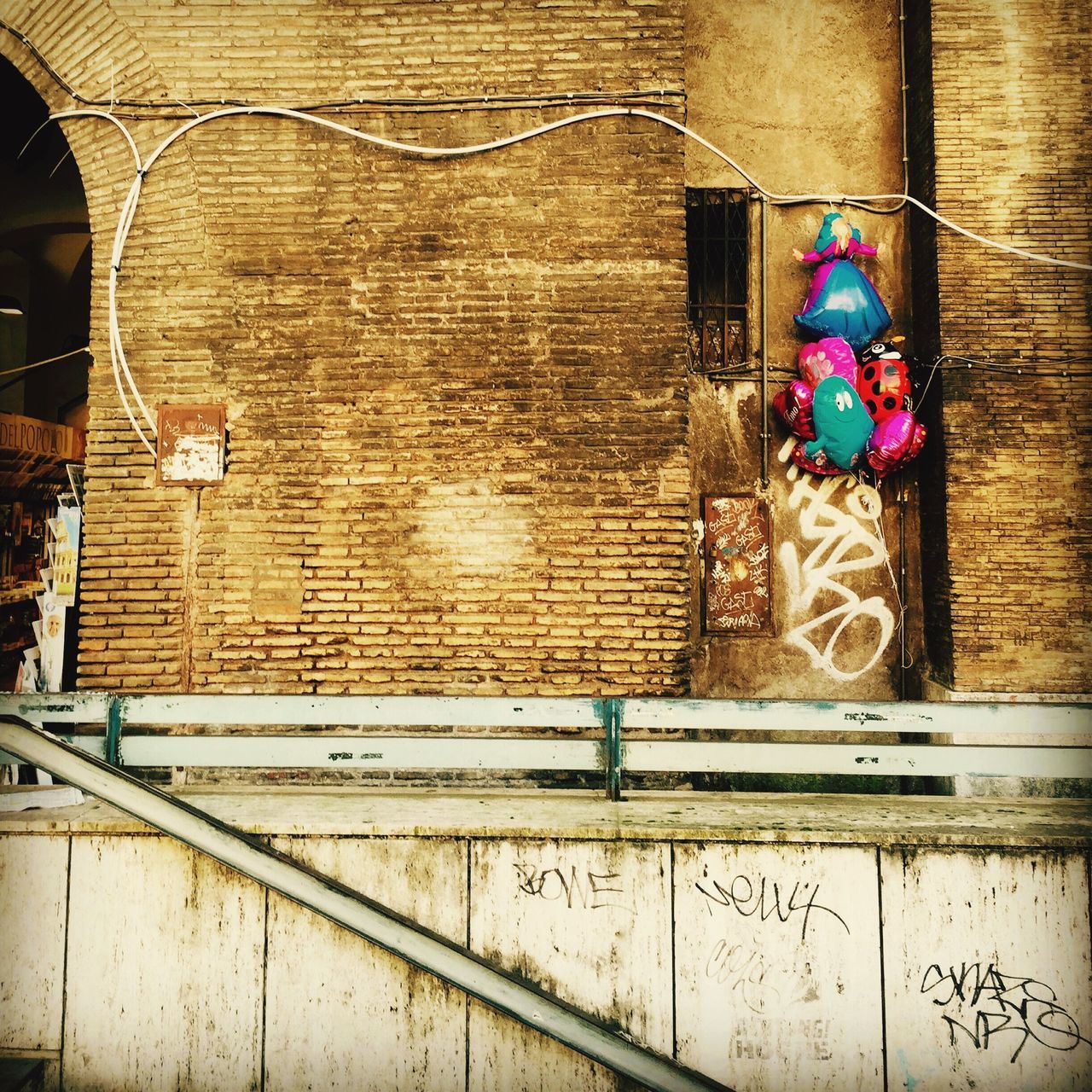 architecture, built structure, building exterior, low angle view, wall - building feature, art and craft, brick wall, window, hanging, building, art, multi colored, day, human representation, outdoors, creativity, no people, blue, wall, railing