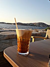 Close-up of drink on table at beach against sky