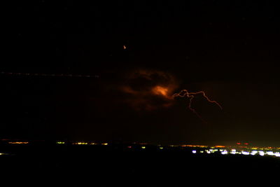 Low angle view of illuminated lights against sky at night