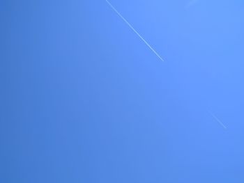 Low angle view of vapor trail against clear blue sky