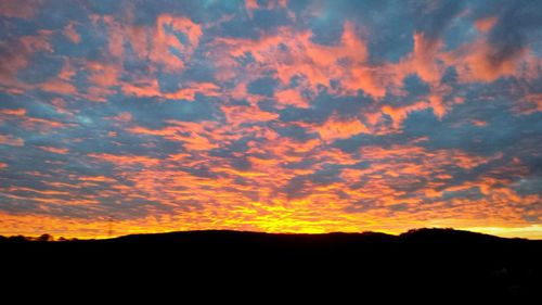 Silhouette landscape against dramatic sky during sunset