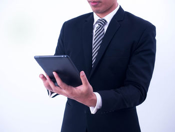 Midsection of man holding smart phone against white background