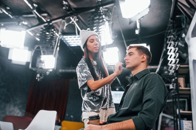Young man is preparing for tv online broadcast. woman helps with make up.