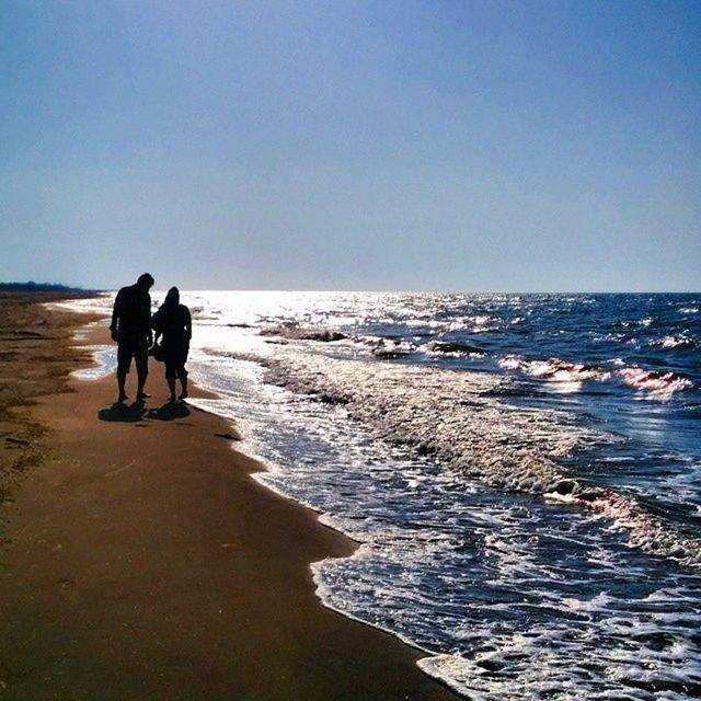 sea, water, horizon over water, beach, clear sky, copy space, shore, men, leisure activity, lifestyles, wave, silhouette, full length, scenics, standing, nature, beauty in nature, vacations