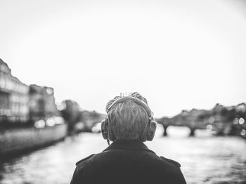 Rear view of woman looking at waterfall against sky