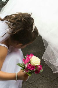High angle view of bride wearing wedding dress while crouching on street