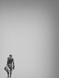 Low angle view of men standing against clear sky