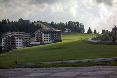 Scenic view of field by buildings against sky