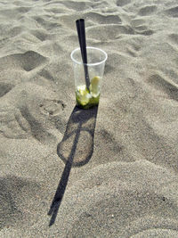 High angle view of beer glass on sand