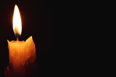 Close-up of lit candle in darkroom