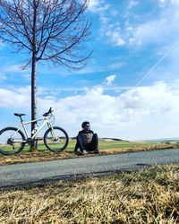 Man riding bicycle on field against sky