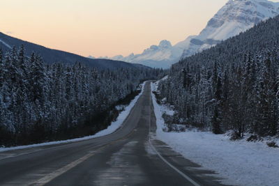 Road amidst snow covered mountains against sky