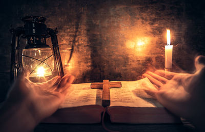 Midsection of man holding illuminated candles on table