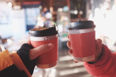 Cropped hands holding disposable coffee cups