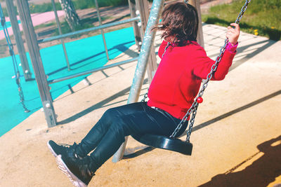 Woman sitting on swing in playground