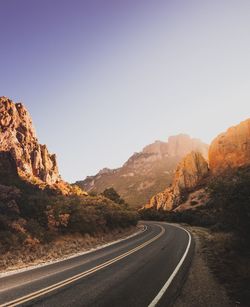 Road passing through mountains against clear sky