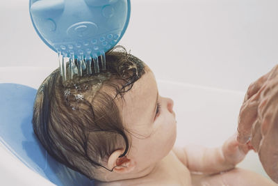 Close-up of hand bathing baby at bathroom