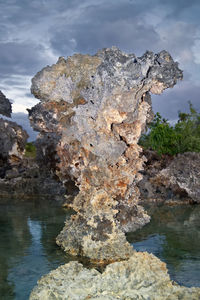 Close-up of rock formation in water against sky