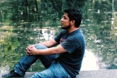 Side view of young man sitting outdoors